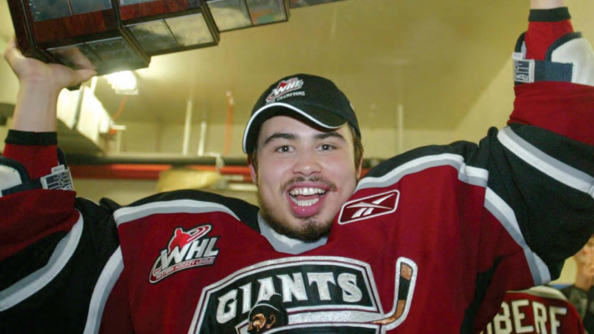 Garet Hunt hoists a trophy over his head while wearing his Giants uniform.